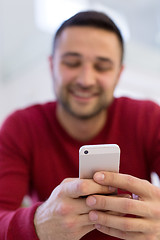 Image showing young man using a mobile phone  at home