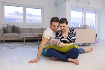 Image showing Young Couple using digital tablet on the floor