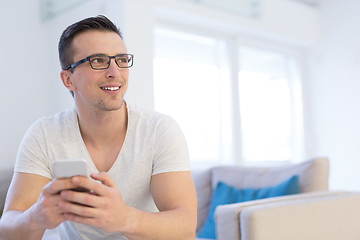 Image showing young man using a mobile phone  at home