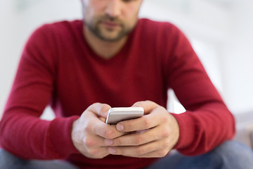 Image showing young man using a mobile phone  at home