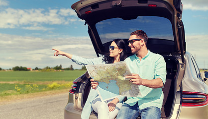 Image showing happy man and woman with road map at hatchback car