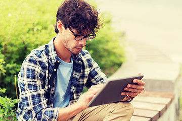 Image showing man with tablet pc sitting on city street bench