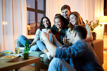 Image showing happy friends with smartphone at home party