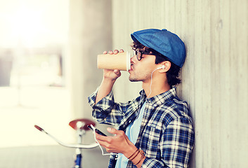 Image showing man with earphones and smartphone drinking coffee