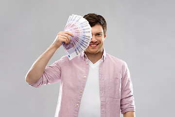 Image showing smiling young man with fan of euro money over grey