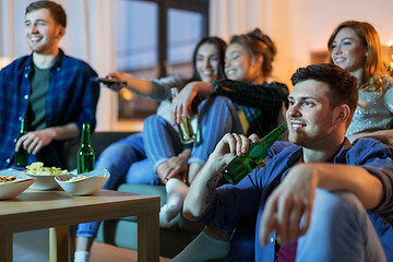 Image showing happy friends with drinks watching tv at home