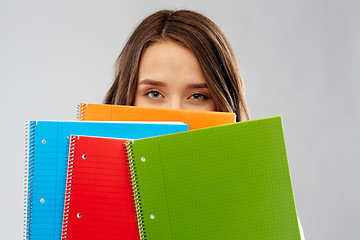 Image showing teenage student girl hiding behind notebooks