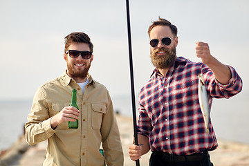 Image showing happy friends with fishing rods and beer on pier