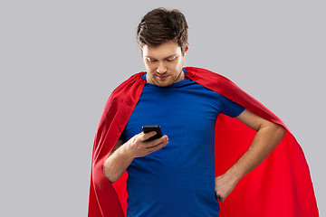 Image showing young man in red superhero cape using smartphone