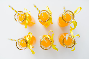 Image showing orange juice in glass bottles with paper straws