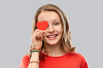 Image showing smiling teenage girl covering eye with red heart