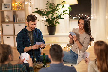 Image showing friends playing cards game at home in evening