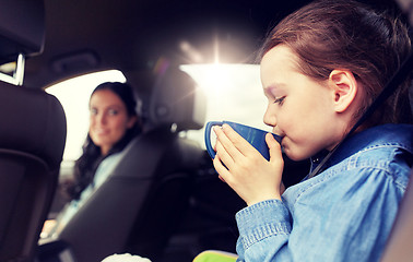 Image showing little girl driving in car and drinking from cup
