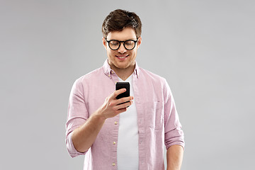 Image showing young man in glasses looking at smartphone