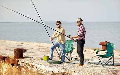 Image showing happy friends with fishing rods on pier