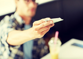 Image showing happy man with cash money paying at cafe