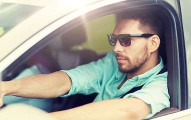 Image showing young man in sunglasses driving car