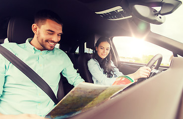 Image showing happy man and woman with road map driving in car