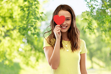 Image showing smiling teenage girl covering her eye by red heart