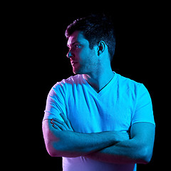 Image showing man with crossed arms over neon lights in darkness