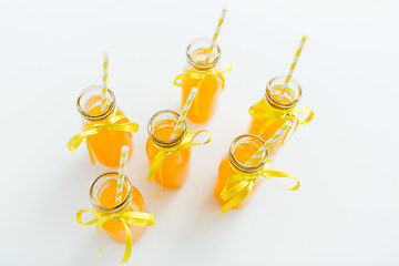 Image showing orange juice in glass bottles with paper straws