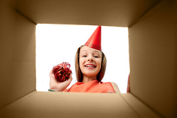 Image showing birthday girl in party hat looking into gift box