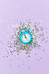 Image showing Alarm clock with twelve hours on a holiday background with silver glitter.