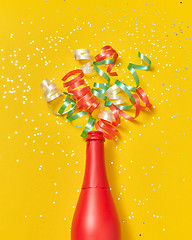 Image showing Colorful paper spirals as a champagne bubbles foam from red painted bottle.