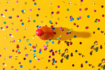 Image showing Holiday background with red painted bottle and colored confetti.