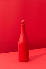 Image showing Red painted spray wine bottle on a duotone red background.