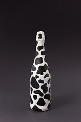 Image showing Holiday painted wine bottle with black spots on a dark gray.