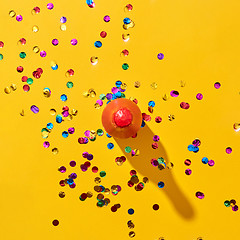 Image showing Top view of red painted bottle with confetti on yellow.