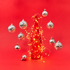 Image showing Wine bottle painted red covered garland with lights and flying balls.