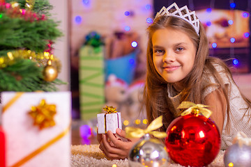 Image showing Girl holding a small pretty gift in her hands, and looks into the frame