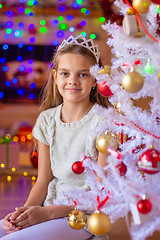 Image showing Beautiful girl sits by a white Christmas tree