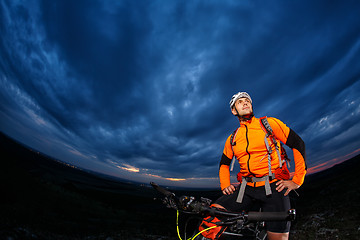 Image showing cyclist standing with mountain bike on trail at sunset