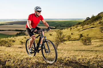 Image showing Young cyclist cycling in the spring meadow