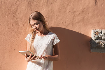 Image showing beautiful young woman in white dress using tablet