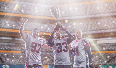 Image showing american football team with trophy celebrating victory in the cu