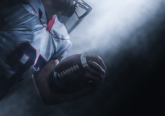 Image showing American football player holding ball while running on field