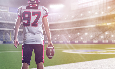 Image showing rear view of young confident American football player on the fie