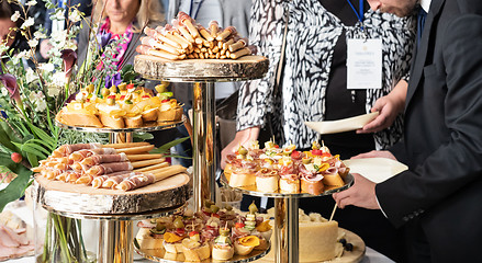 Image showing Businesspeople at banquet lunch break at business conference meeting. Assortment of canapes and finger food on the table.