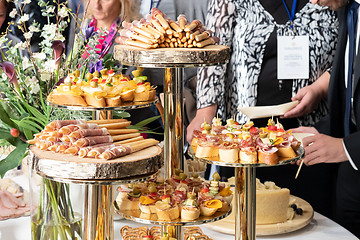 Image showing Businesspeople at banquet lunch break at business conference meeting. Assortment of canapes and finger food on the table.