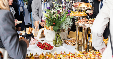 Image showing Businesspeople at banquet lunch break at business conference meeting. Assortment of canapes and finger food on the table.
