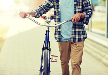 Image showing close up of man with bicycle walking along city