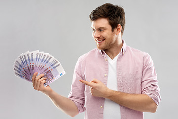 Image showing smiling young man showing fan of euro money