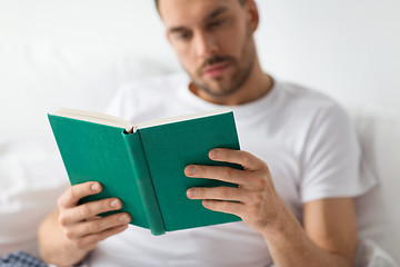 Image showing close up of man in bed reading book at home