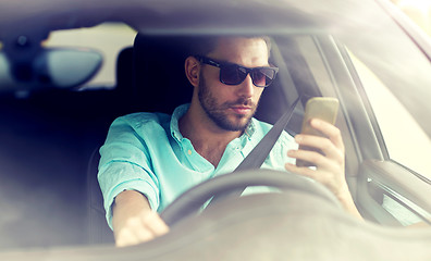 Image showing man in sunglasses driving car with smartphone