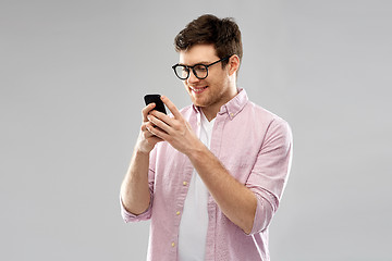 Image showing young man in glasses looking at smartphone