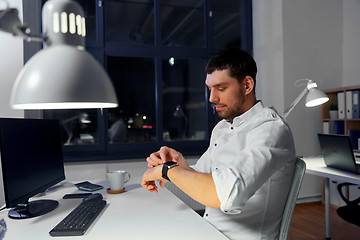 Image showing businessman using smart watch at nigh office